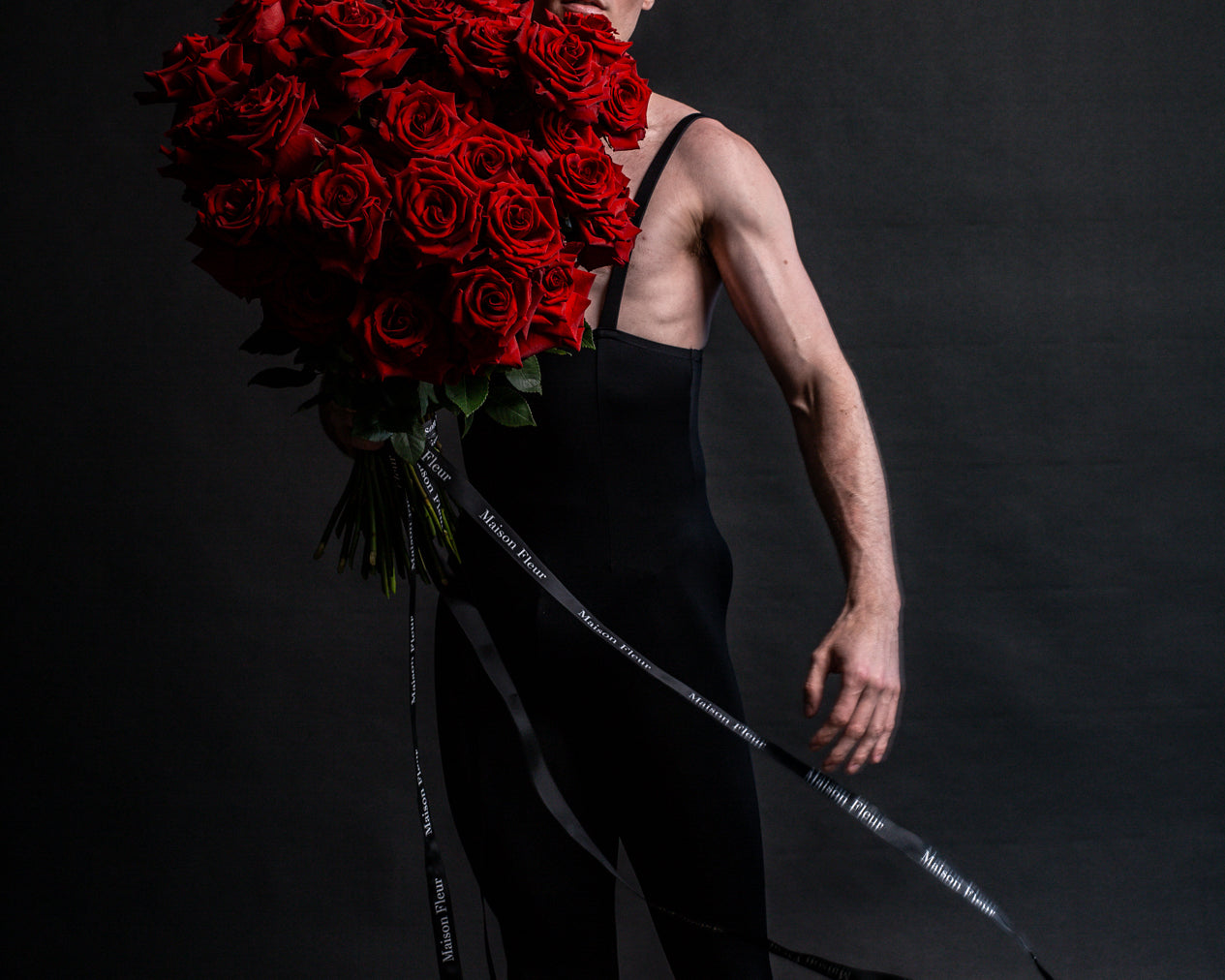 Male Ballerina wearing black holding a large bouquet of red roses
